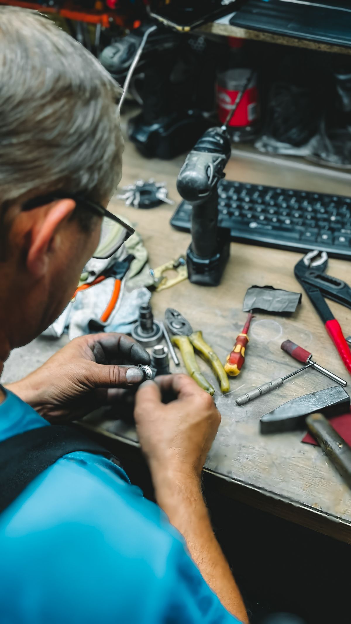 A worker repairing tools at a workshop desk